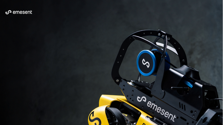 Close-up of an Emesent drone sensor frame in yellow and black, with a blue circular logo component on a dark background?
